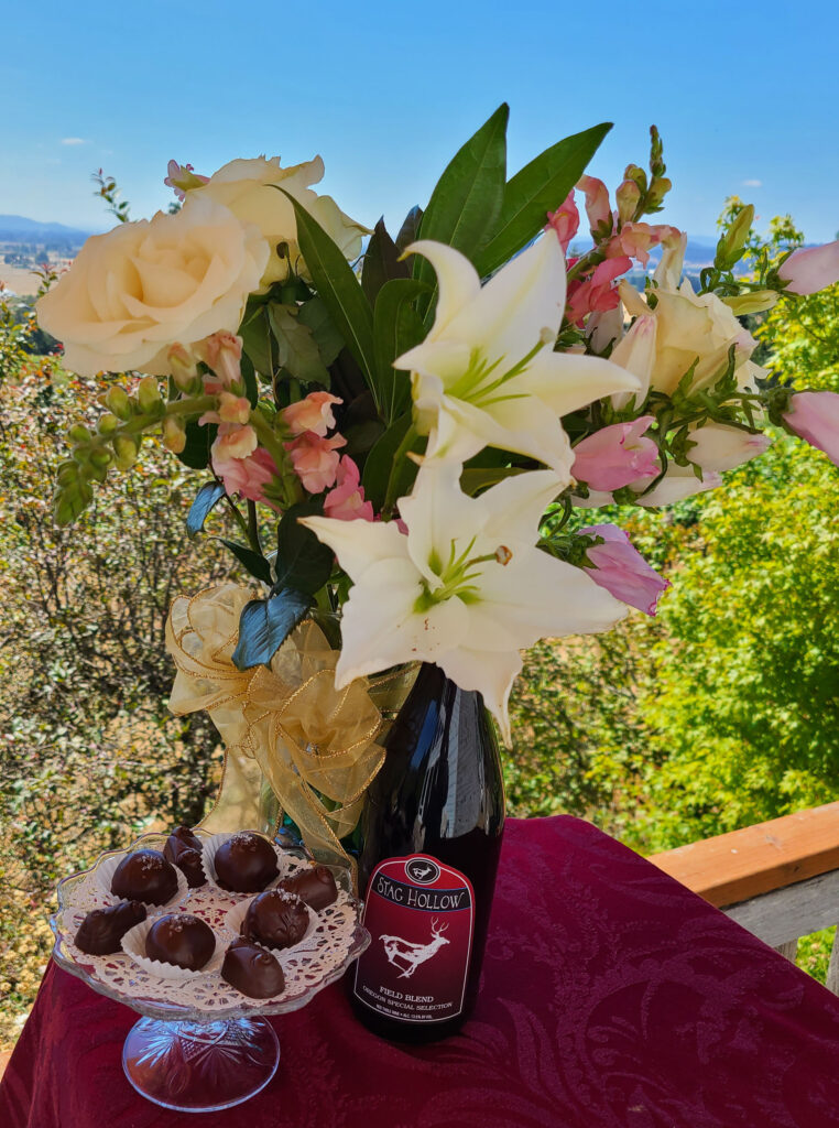 flower bouquet with a bottle of wine and a plate of chocolates